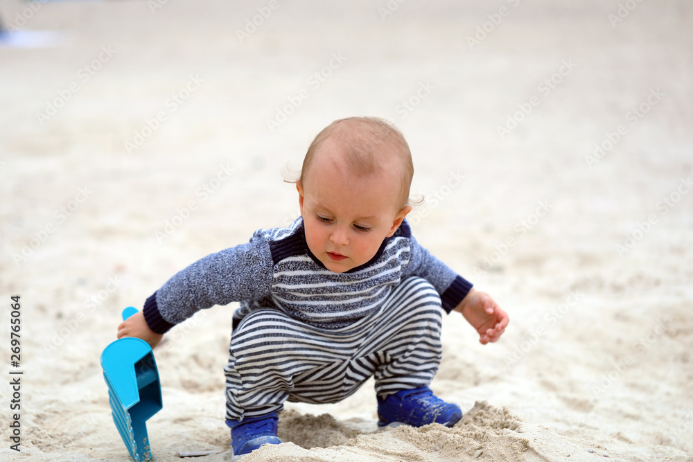 Baby Is Playing With Sand And Plastic Shovel On The Beach Baby Is Playing With Sand And Plastic Shovel On The Beach