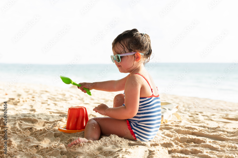 Little Girl Making Sand Castle On Beach - obrazy, fototapety, plakaty 