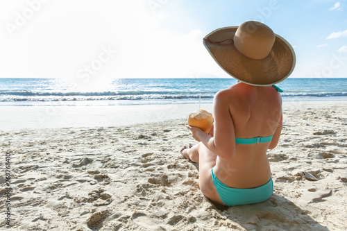 Woman Sitting On Beach Holding Coconut In Hand