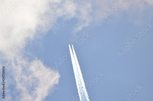 airplane with contrail in sunny sky at very high altitude