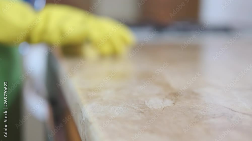 Housekeeper washes the kitchen table. A woman with a sponge in yellow gloves washes the kitchen table. Housekeeper washes the kitchen table. A woman with a sponge in yellow gloves washes the kitchen table.