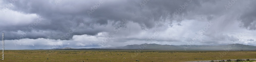 Landscape stormy panorama view from the border of Utah and Idaho from Interstate 84, I-84, view of rural farming with sheep and cow grazing land in the Rocky Mountains. United States.