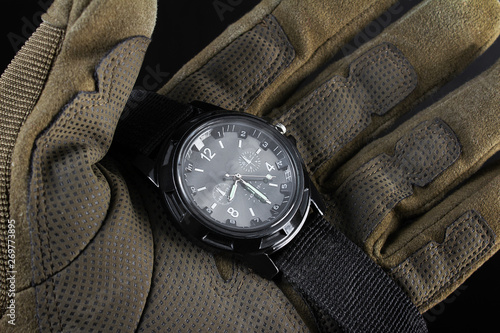 Soldier arm holding black tactical watch close up.