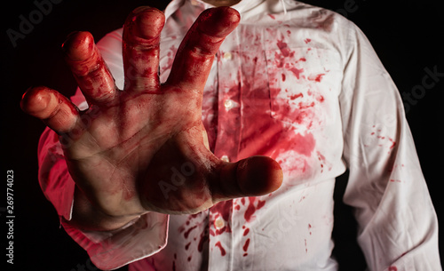 Man in white bloody shirt reaching out hand.