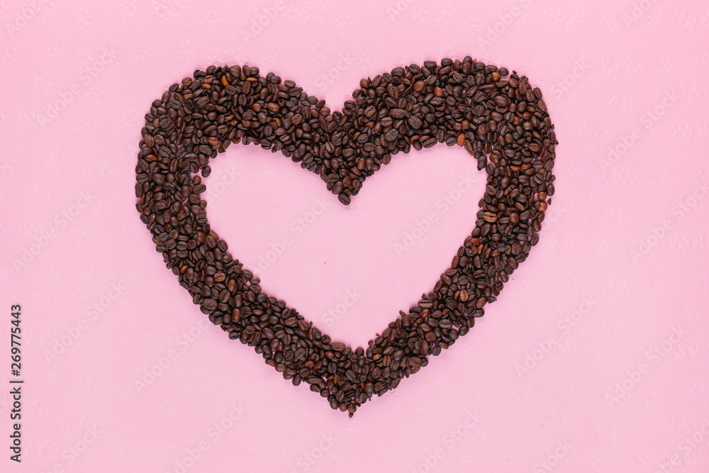 Heart from coffee beans on pink background