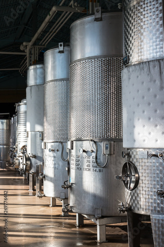 Closeup of Row of Insulated Cold Storage Tanks for Beer or Wine with Overhead Pipes