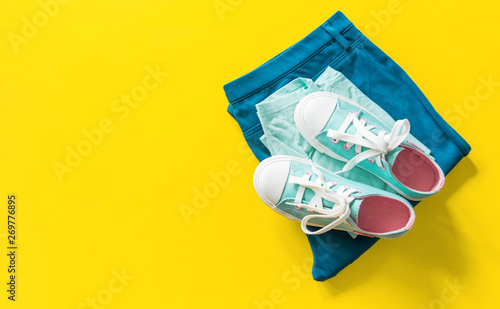 New turquoise sneakers on yellow background with copy space.