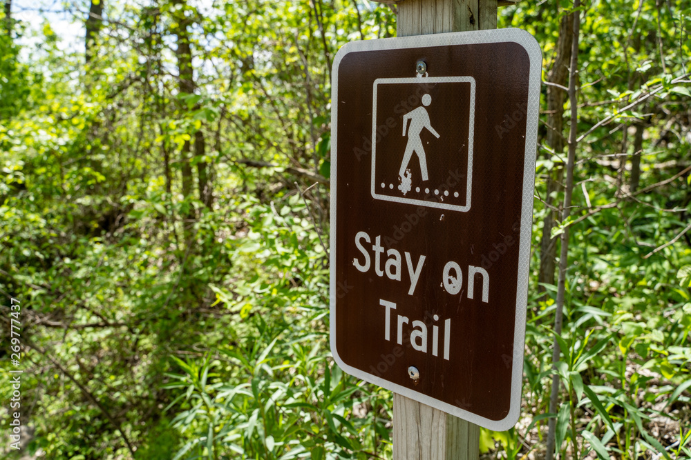 Sign warning and reminding hikers to stay on the trail Sign warning and reminding hikers to stay on the trail