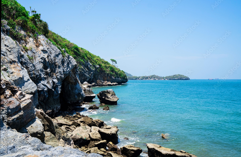 At seaside in summer ,waves on stone beach shore . blue sea blue sky background .Travel, Vacation and Holiday concept . Tropical beach .