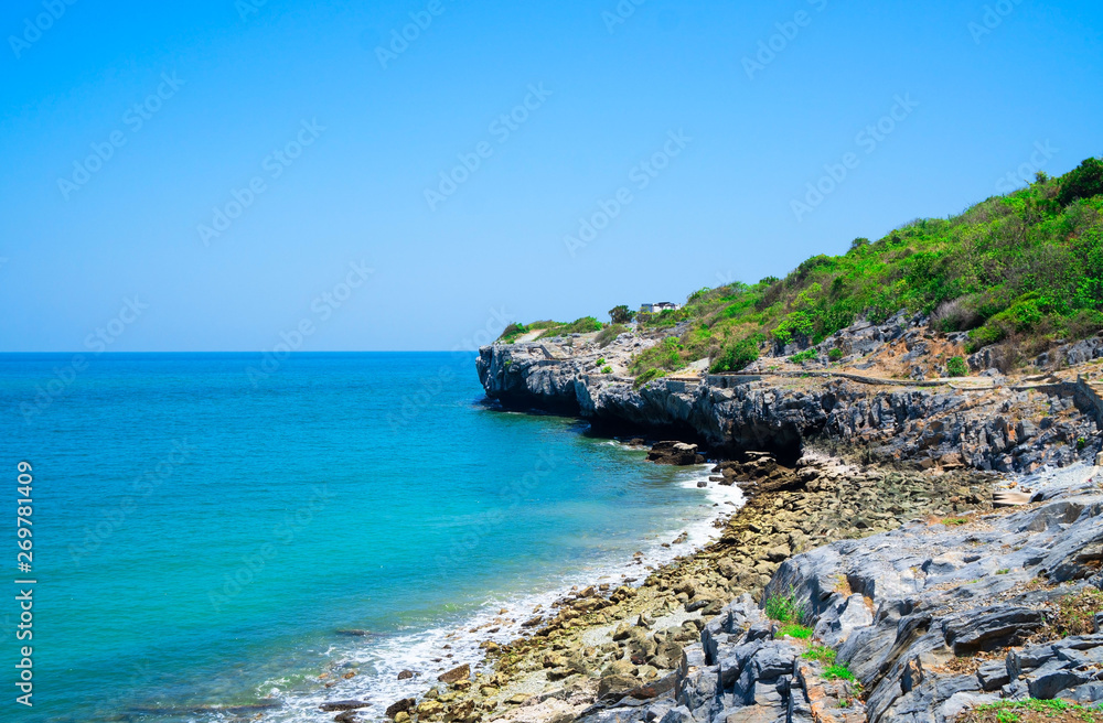At seaside in summer ,waves on stone beach shore . blue sea blue sky background .Travel, Vacation and Holiday concept . Tropical beach .
