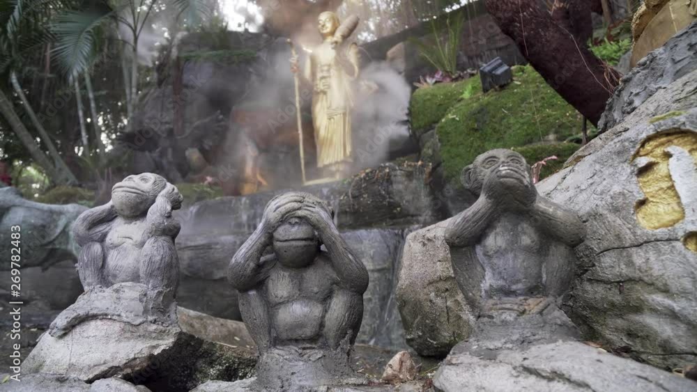 Static shot of three wise monkeys at golden mount temple Thailand, Bangkok. See no evil, hear no evil, speak no evil statues in exterior, outside shrine with flowing misty water features. Static shot of three wise monkeys at golden mount temple Thailand, Bangkok. See no evil, hear no evil, speak no evil statues in exterior, outside shrine with flowing misty water features.