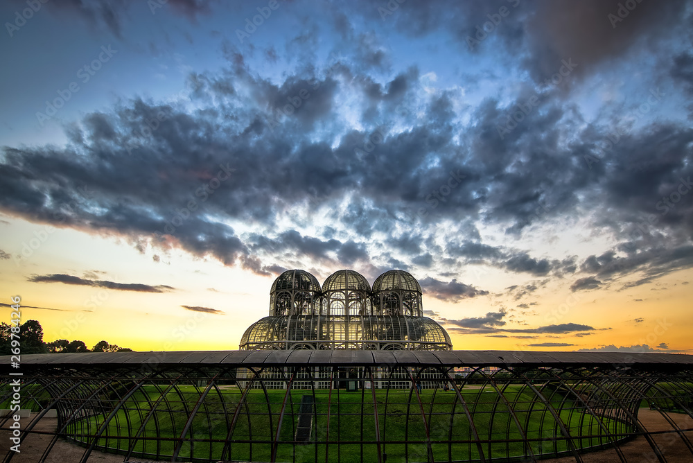 Fototapeta premium Botanical Garden of Curitiba. Beautiful day with some clouds in the sky. In the image the sunset and the greenhouse with many flowers.
