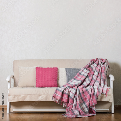 Beige sofa with plaid and colorful pillows (pink, grey, white) in the living room.