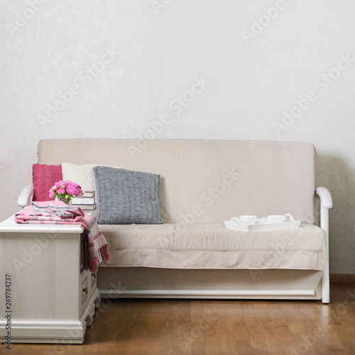 Fototapeta Naklejka Na Ścianę i Meble -  Beige sofa with pillows in the living room and vase with Flowers (Michaelmas daisy, asters).