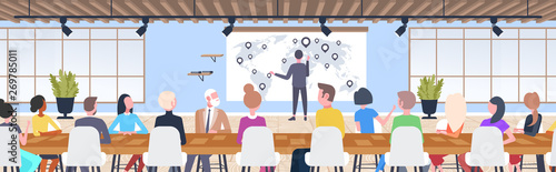 businessman pointing geo tag on world map to colleagues businesspeople sitting round table conference meeting presentation concept modern co-working office interior flat horizontal full length
