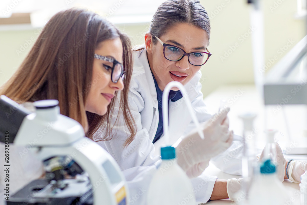 Two young woman working in laboratory preparing for analyze Two young woman working in laboratory preparing for analyze