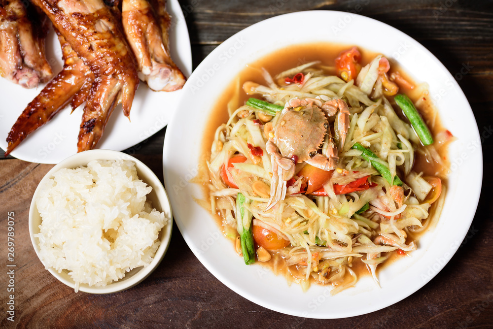 Spicy green papaya salad,grilled chicken wing and sticky rice. Thai food (Som Tum)