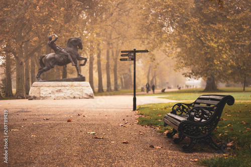 Autumn. Lonely bench next to Physical Energy Statue in Hydepark. sadness, melancholy, gloom, loneliness. photo