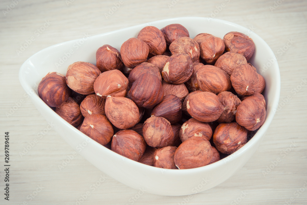 Hazelnuts in white bowl, healthy nutrition and lifestyle concept Hazelnuts in white bowl, healthy nutrition and lifestyle concept