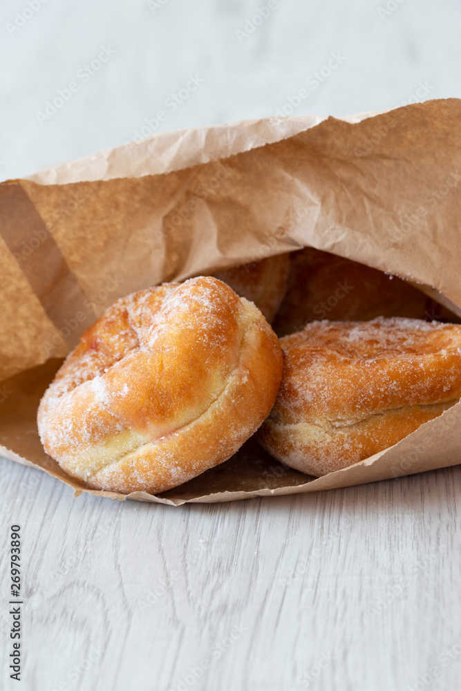 Jam doughnuts in a brown paper bag,  recycling packaging,  on a grey wood background