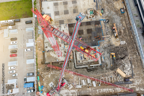 Installation of a construction crane, with the help of a crane on a truck, aerial top view of the pit and building site, the foundation.