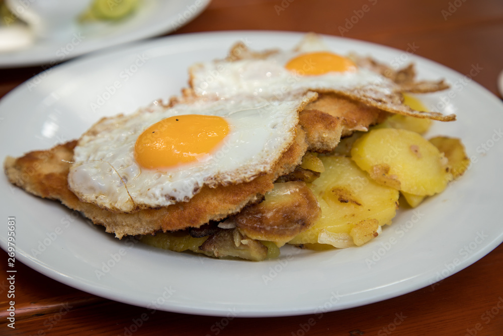 Schweine Fleisch Schnitzel Wiener Art mit Spiegelei als Hamburger dazu Bratkartoffeln im Biergarten Restaurant Schweine Fleisch Schnitzel Wiener Art mit Spiegelei als Hamburger dazu Bratkartoffeln im Biergarten Restaurant