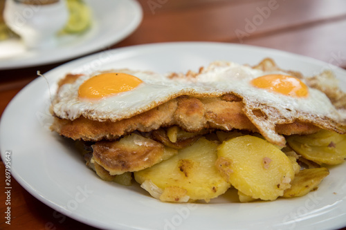 Schweine Fleisch Schnitzel Wiener Art mit Spiegelei als Hamburger dazu Bratkartoffeln im Biergarten Restaurant