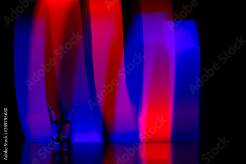 glass of vodka on the background of the abstraction of colored stripes