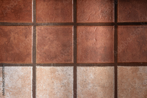 Warm-colored ceramic tiles decorate a wall; one line of lighter color adds visual cadence to the otherwise monotonous design.