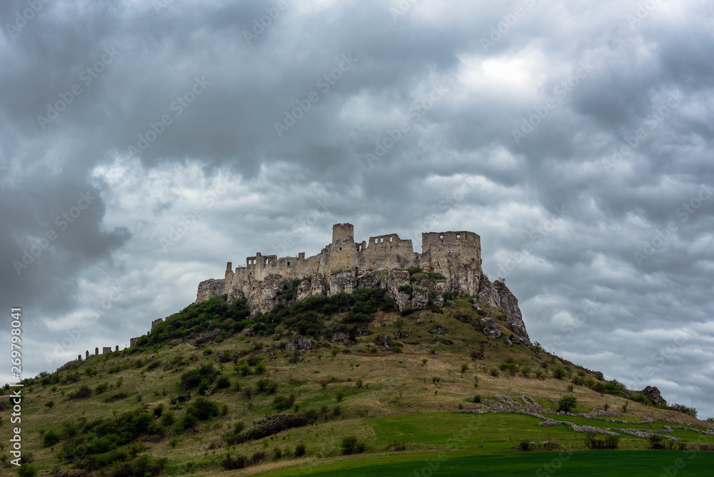 Ruins of an ancient royal castle on a high hill under a cloudy spring sky