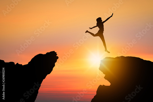 freedom and possible concept, silhouette people jumping over rock mountain successfully