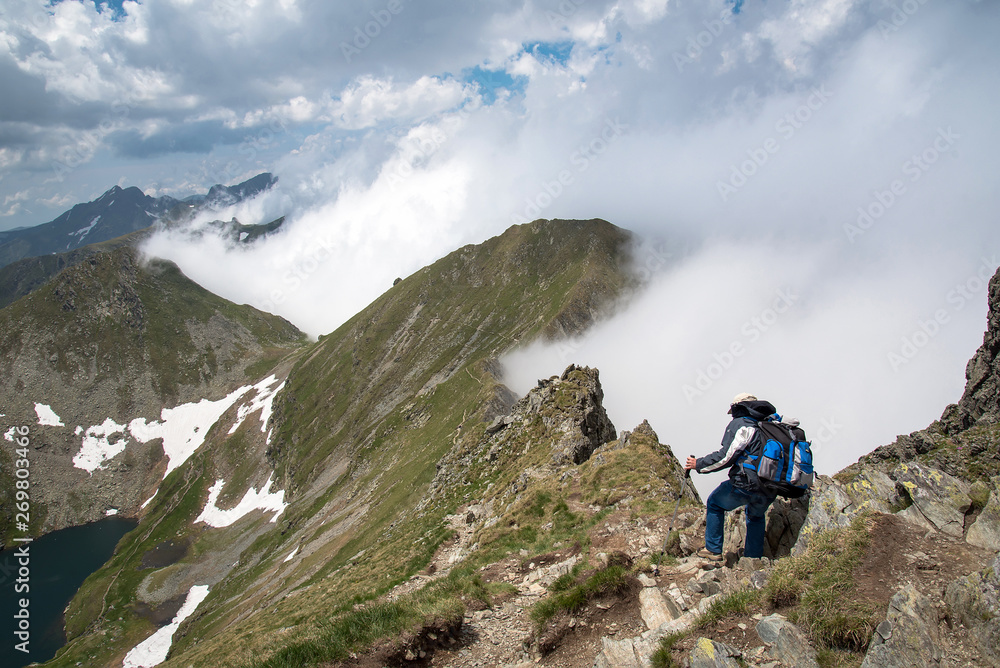 the tourist moves along a ridge covered with clouds