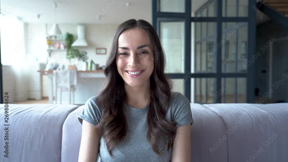 Relax and concentrate at home. Portrait of smiling cute lovely brunette woman in casual clothes while she sitting on sofa at home and looks on camera. Relax and concentrate at home. Portrait of smiling cute lovely brunette woman in casual clothes while she sitting on sofa at home and looks on camera.