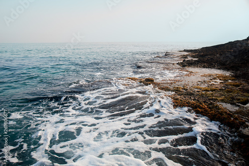 Aerial top view of sea waves hitting rocks on the beach with turquoise sea water. Amazing rock cliff seascape in the coastline. Aerial view of sea waves and fantastic Rocky coast. Mediterranean Sea.