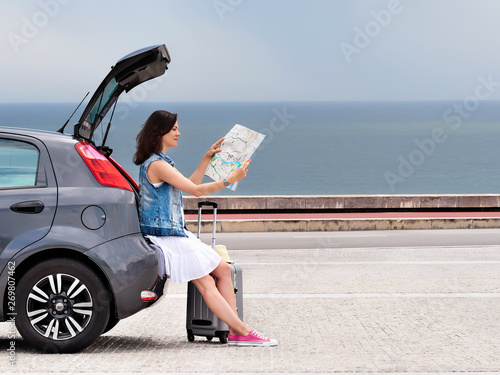 Foto Woman traveler on hatchback car on seaside road.
