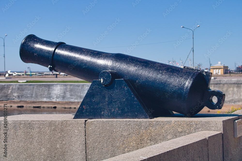 Black old cast-iron cannon for firing cores installed on the granite embankment Black old cast-iron cannon for firing cores installed on the granite embankment