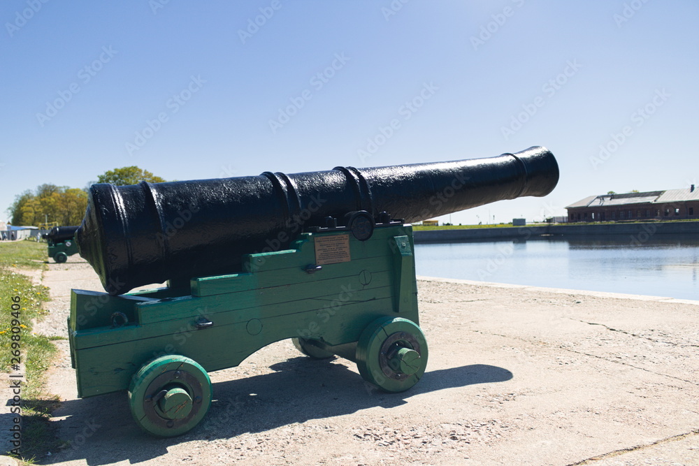 Old black old cast-iron cannon for firing cores mounted on a wooden carriage on the shore of the bay