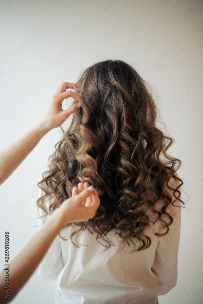 Closeup of female hands of hairdresser or coiffeur makes hairstyle Closeup of female hands of hairdresser or coiffeur makes hairstyle