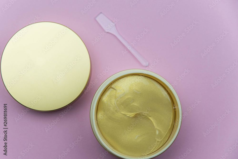 Hydrogel cosmetic eye patch jar with golden patches against dark circles under eyes with spoon. Beauty health care concept. Flat lay set on pink background. Hydrogel cosmetic eye patch jar with golden patches against dark circles under eyes with spoon. Beauty health care concept. Flat lay set on pink background.