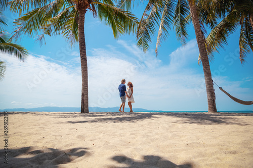Beautiful young couple walking along the seashore amid a bright tropical beach