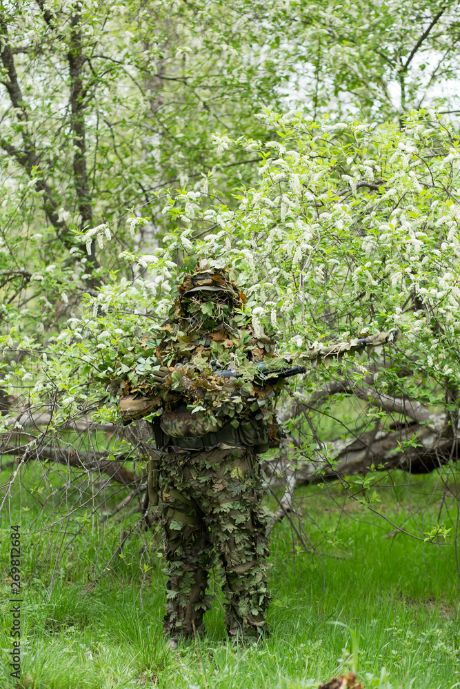 Fototapeta premium Camouflaged sniper in the forest