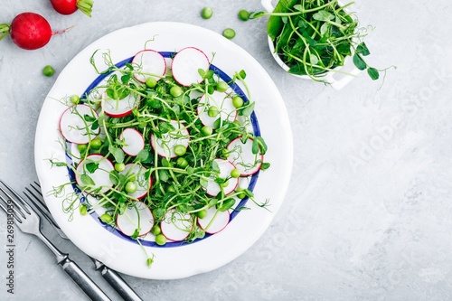 Fresh summer green pea shoots salad with radishes. Top view