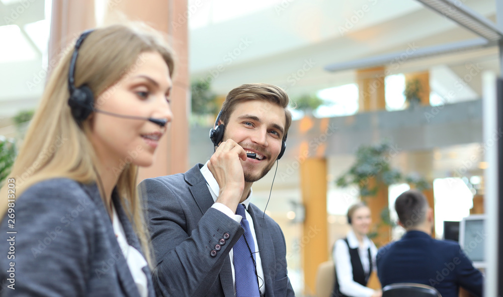 Portrait of call center worker accompanied by his team. Smiling customer support operator at work. Portrait of call center worker accompanied by his team. Smiling customer support operator at work.