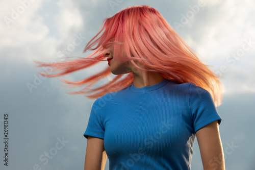 Woman toss her pink hair over sky background, creative art portrait photo