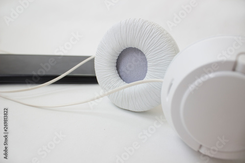 White headphones and black phone on a light background.