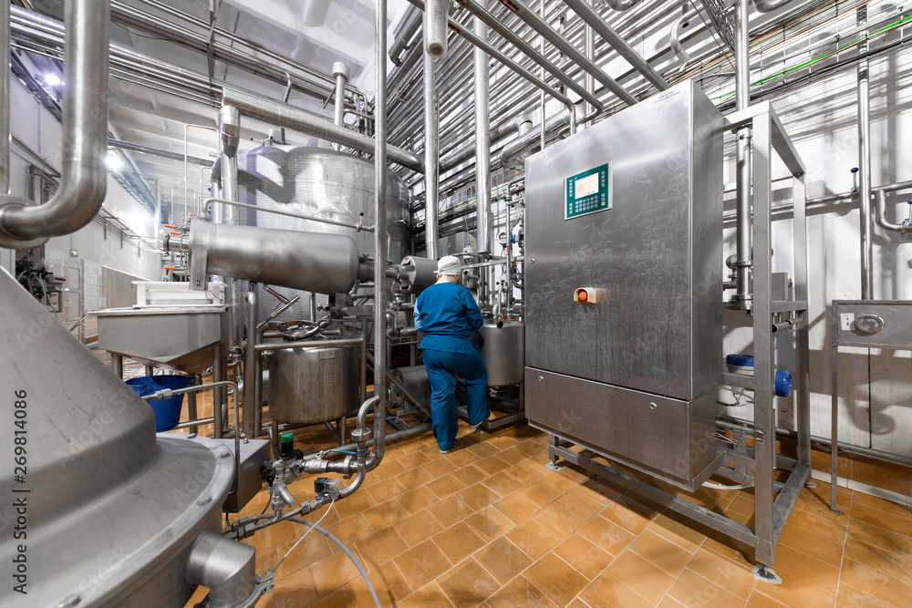 worker in a blue robe and a cap inspect the production department of dairy factory worker in a blue robe and a cap inspect the production department of dairy factory