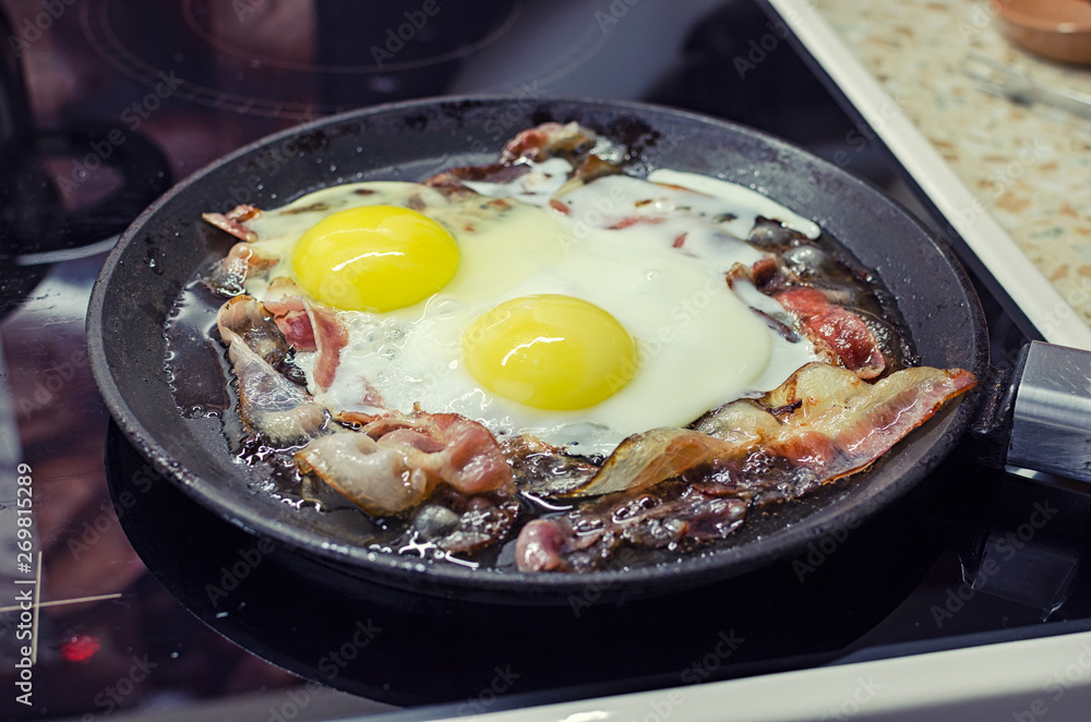 scrambled eggs cooking in a frying pan, cooking on a ceramic stove, scrambled eggs with bacon, 45 view closeup scrambled eggs cooking in a frying pan, cooking on a ceramic stove, scrambled eggs with bacon, 45 view closeup