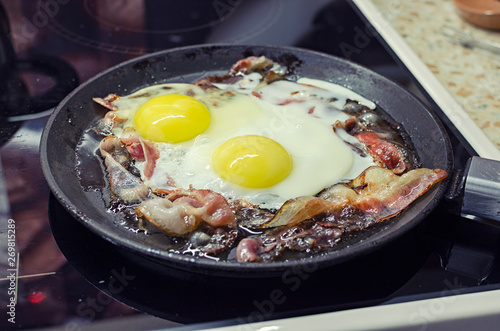 scrambled eggs cooking in a frying pan, cooking on a ceramic stove, scrambled eggs with bacon, 45 view closeup
