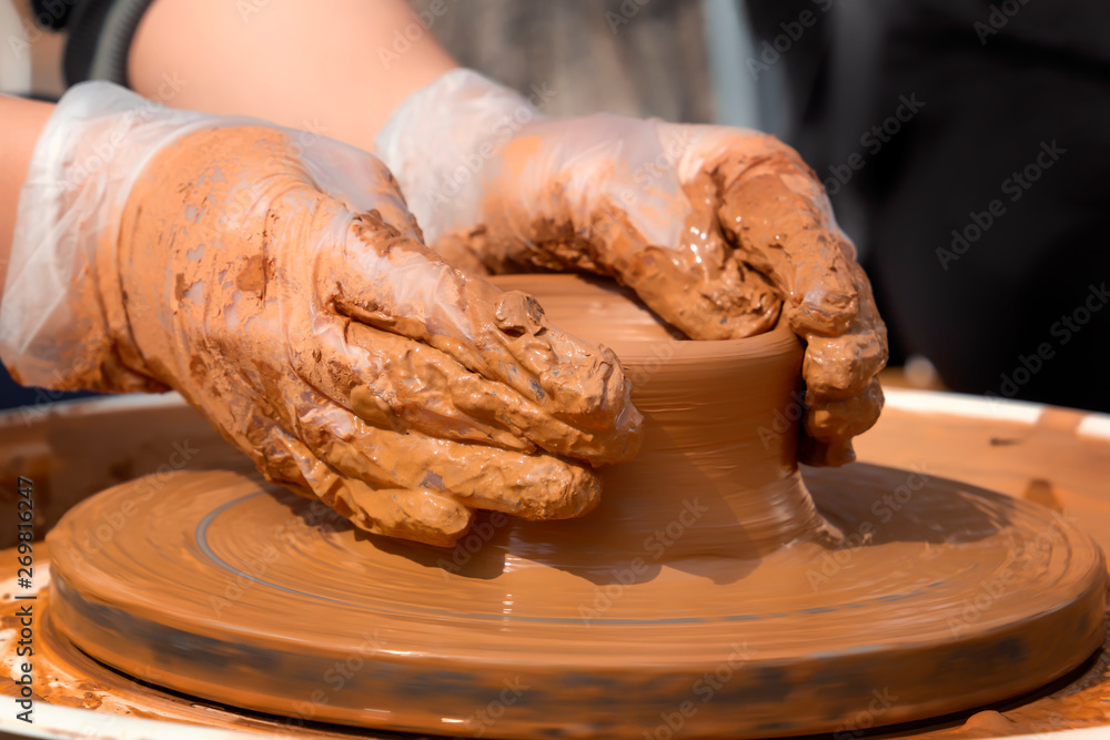 hands of the potter make the product out of clay on a potter's wheel. Close-up