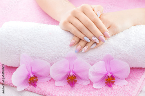 beautiful colored manicure with decor  orchid  towel and candle on the white wooden table. spa